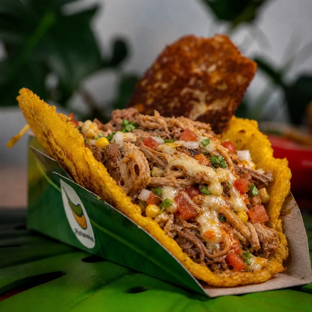 La Trifásica: tostón pintón con res, cerdo, pollo, teriyaki, hogao, queso gratinado, champiñón, aguacate y papa chips